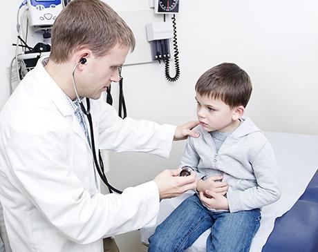 Doctor checking boy holding stomach