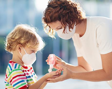 Woman helping child sanitize hands